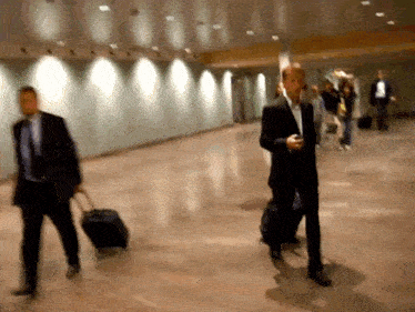 a man in a suit is pulling a suitcase