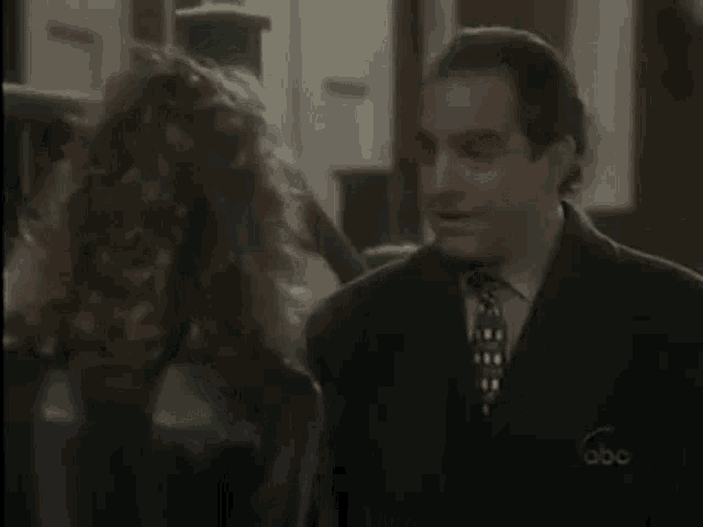 a man in a suit and tie is talking to a woman in a leather jacket .