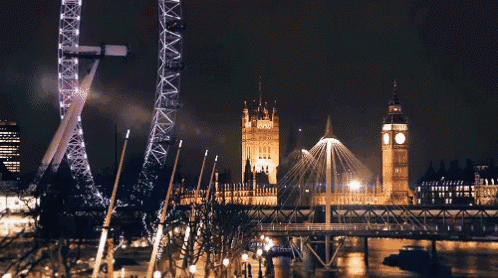 a large ferris wheel is lit up at night in front of big ben