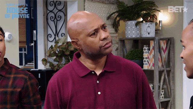 a man in a maroon shirt is standing in front of a sign that says bet