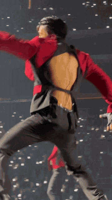 a man in a red jacket and black pants has a cut out in his back