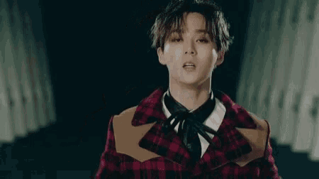 a close up of a young man wearing a plaid jacket and a black tie .
