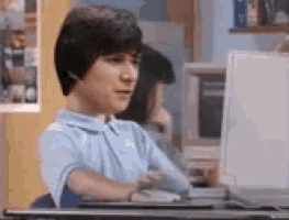 a young boy is sitting at a desk in front of a computer monitor .