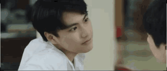 a young man in a white shirt is looking at another man .