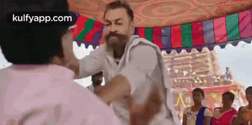 a man with a beard is fighting another man in front of a group of people .