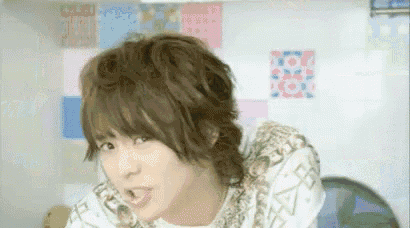 a young man with long hair is making a funny face while looking at the camera .