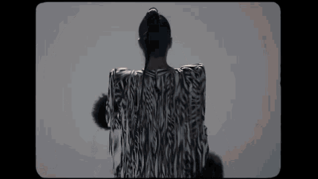 a woman in a zebra print dress is standing in front of a white wall .