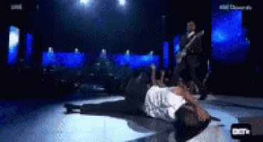 a man is laying on the floor on a stage in front of a crowd