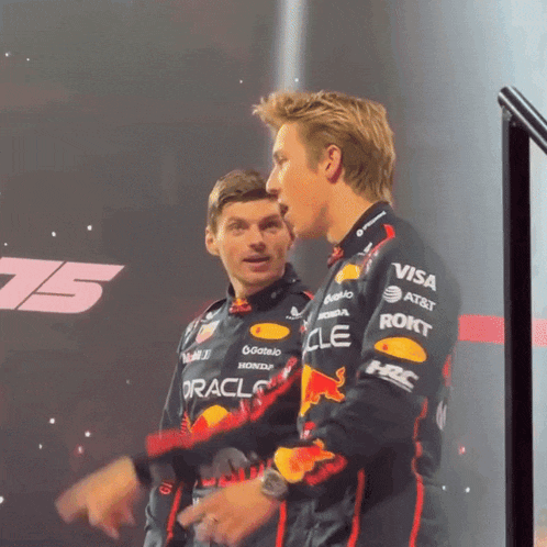 a man in a red bull racing uniform is talking to another man