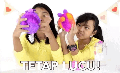 two girls holding stuffed animals with the words tetap lucu on the bottom right