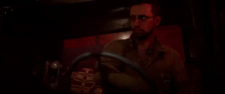a man wearing glasses is driving a car in a dark room .