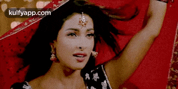 a woman is laying on a bed with her arms outstretched and a red cloth covering her face .