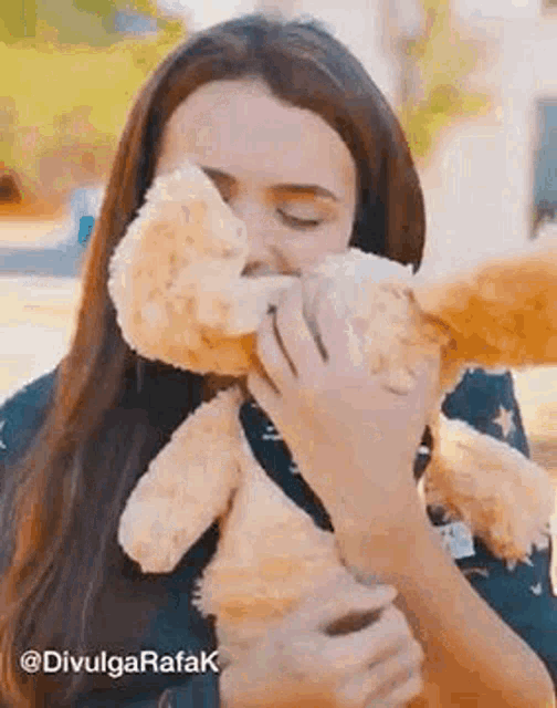 a woman is kissing a teddy bear on the nose .