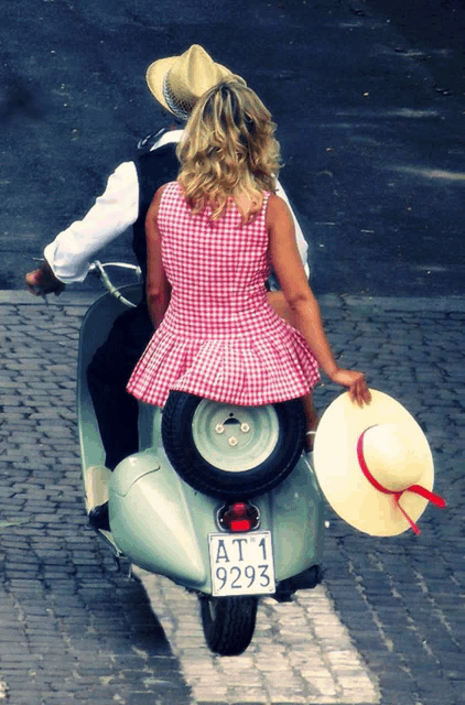 a man and a woman are riding a scooter with a license plate that says at1 9293