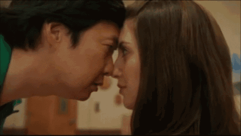 a man and a woman are looking at each other 's faces and kissing .