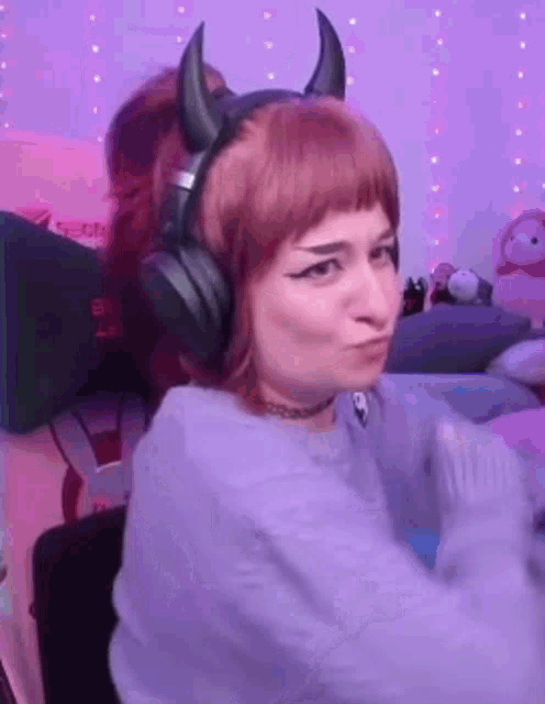 a woman wearing headphones and horns is making a face .