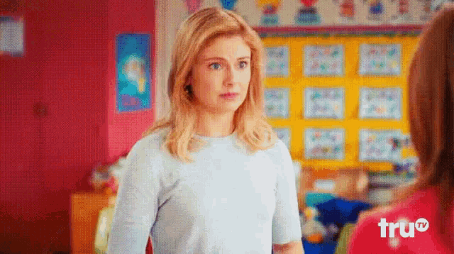 a woman in a blue shirt is standing in front of a bulletin board that says " true "