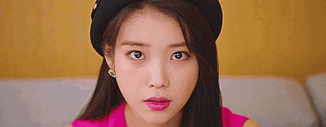 a close up of a woman wearing a black hat and pink lipstick .