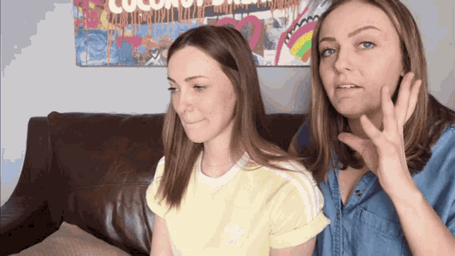 two women are sitting on a couch and one of them is wearing a yellow adidas t-shirt