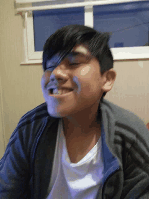 a young boy wearing a gray adidas jacket is smiling
