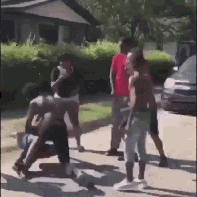 a group of young men are fighting on the side of a street .