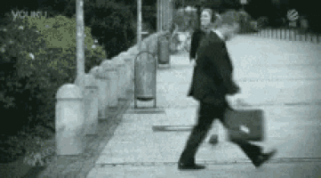 a man in a suit is walking down a sidewalk carrying a briefcase