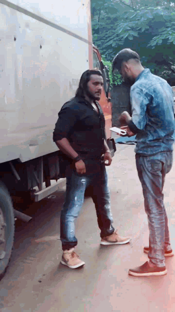 two men are standing next to each other on a street