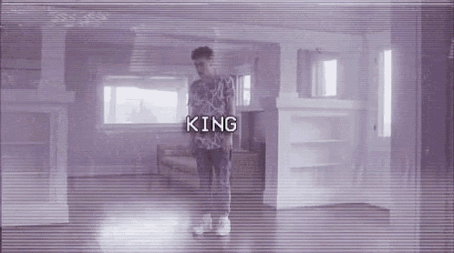 a man is standing in a room with the word king written on the screen .