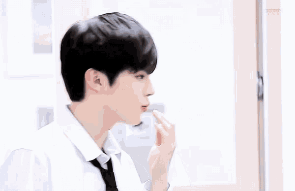 a young man wearing a white shirt and black tie is eating something