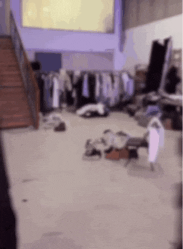 a very messy room with a lot of clothes on the floor and stairs .