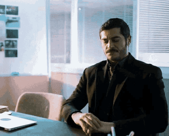 a man in a suit and tie is sitting at a desk