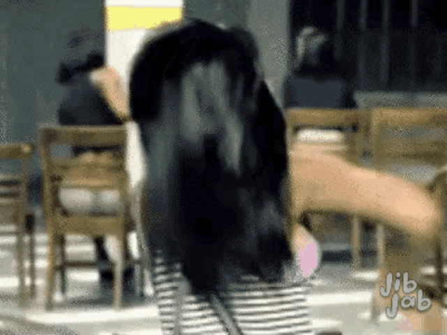 a woman is dancing in front of a group of chairs in a room .