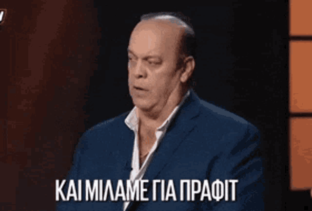 a man in a blue suit is sitting in front of a microphone and talking in a foreign language .