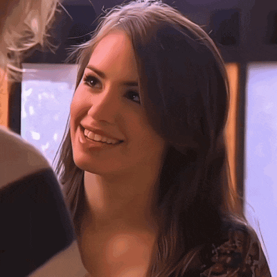 a woman with long brown hair is smiling and looking at another woman