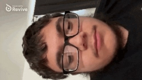 a man wearing glasses and a black shirt with the words made with revive on the bottom