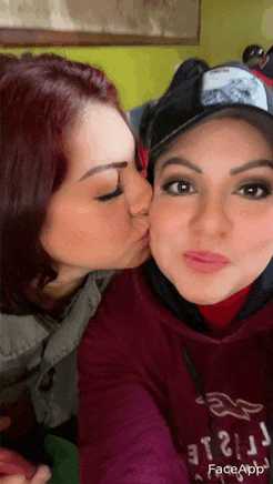 a woman wearing a hollister shirt is kissing another woman