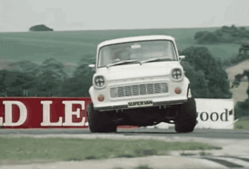 a white supervan is driving down a track