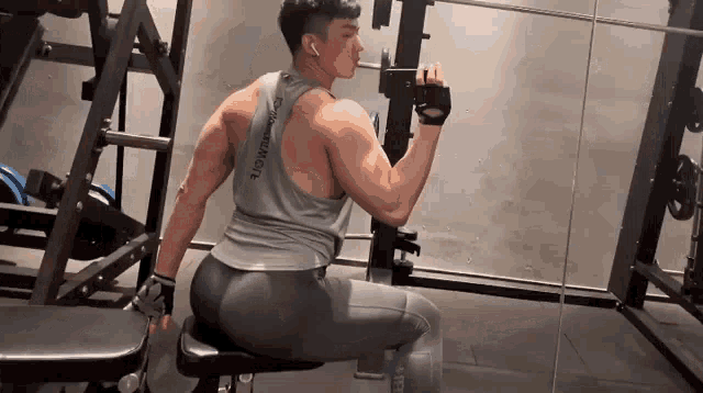 a man is sitting on a bench in a gym while lifting weights .
