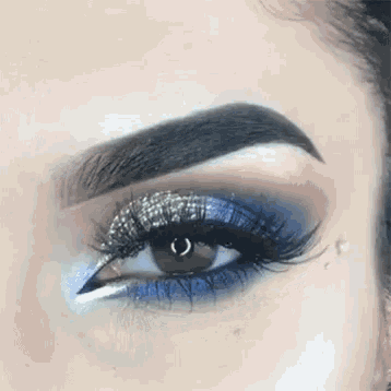 a close up of a woman 's eye with blue eyeshadow