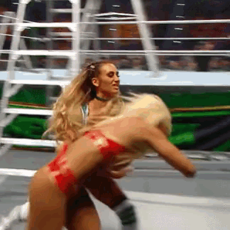 two women are wrestling in a ring with a green background