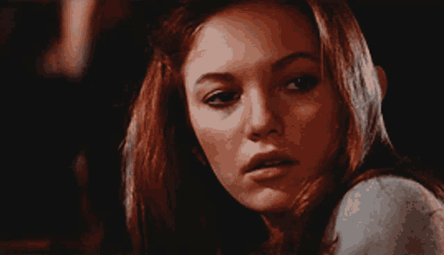 a woman with red hair is looking at the camera