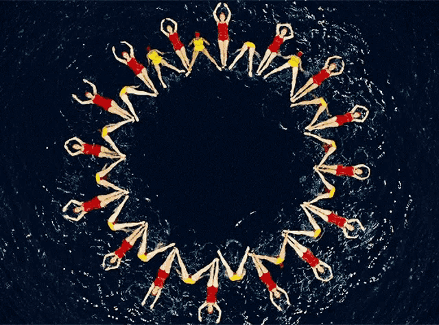 a group of people swimming in a circle with their arms outstretched