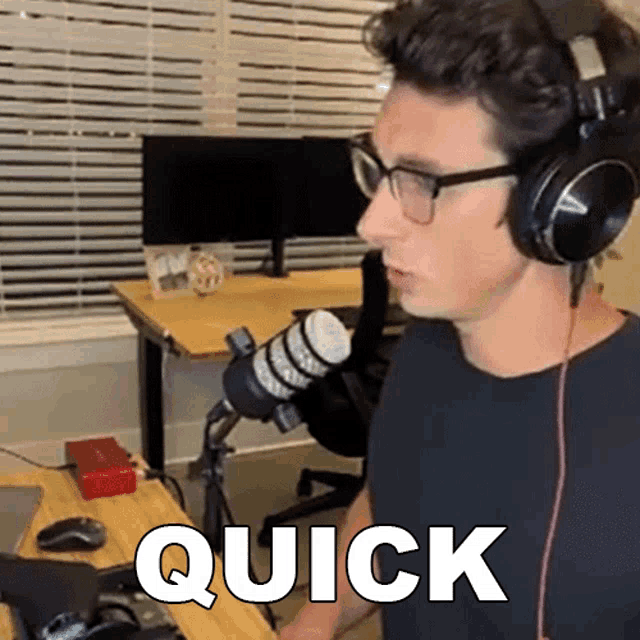 a man wearing headphones and glasses is sitting in front of a microphone with the word quick written in white