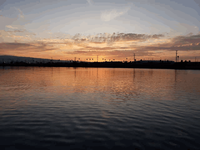 a sunset over a body of water with a few buildings in the background