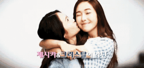 a woman kissing another woman on the cheek with a foreign language behind them