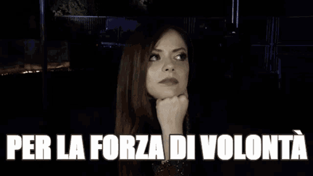 a woman is making a funny face in a dark room with the words `` per la forza di volonta '' above her .