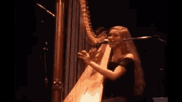 a woman is playing a harp in front of a microphone .