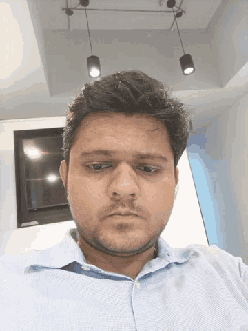 a man with a beard and a blue shirt looks at the camera