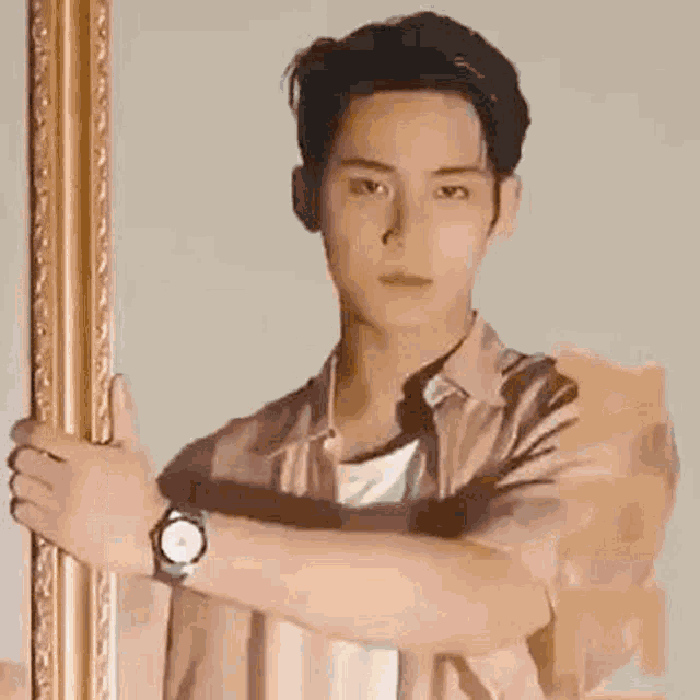a man wearing a watch is standing next to a picture frame .