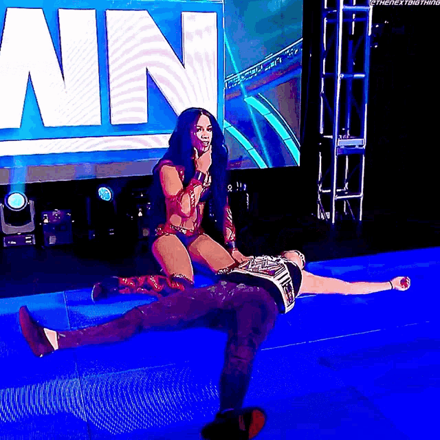 a woman is kneeling on a man 's back in front of a sign that says ' win '